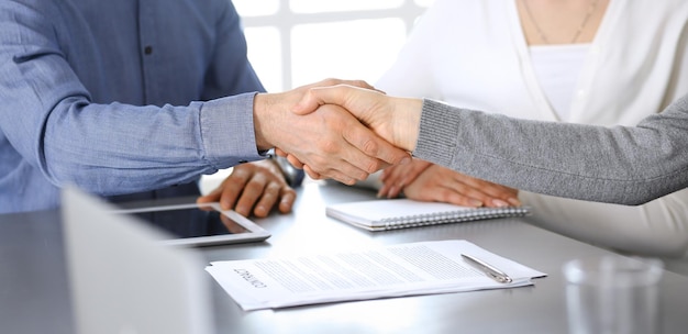 Group of business people shaking hands after discussing questions and achieving agreement at meeting in modern office. Handshake close-up. Teamwork, partnership and business concept.