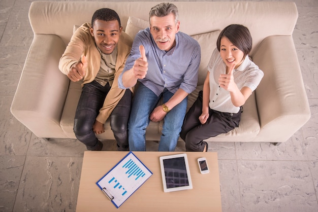 Group of business people showing thumbs up at office.