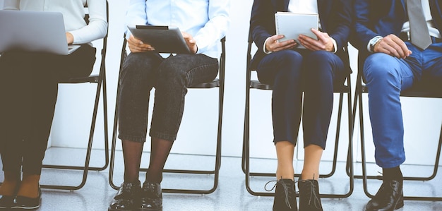 Group of business people sitting in office and waiting for job\
interview while using gadgets. conference or training\
concepts.