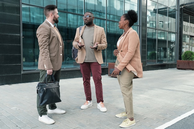 Group of business people talking to each other while standing near the office building in the city