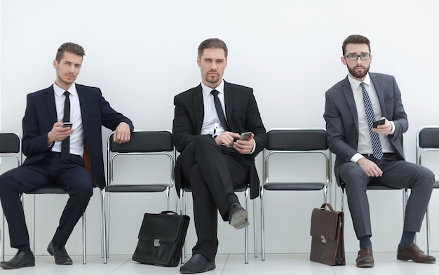 Group of business people with smartphones sitting in the office hallwayphoto with copy space