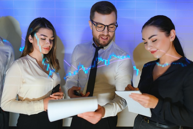 近代的なオフィスで働くビジネスマンのグループ技術的な価格グラフの赤と青のローソク足チャートと株式取引のコンピューター画面の背景 二重露出 データを分析するトレーダー