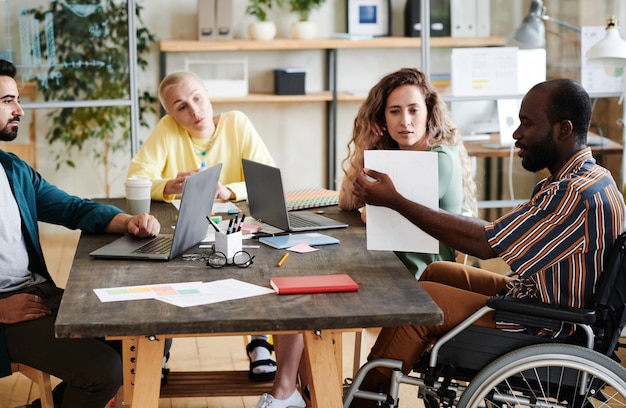 Group of business people working in team they sitting at the table with computers and talking to each other during meeting at office