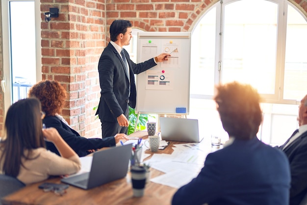 Group of business workers smiling happy and confident in a meeting Working together looking at presentation using board and charts at the office