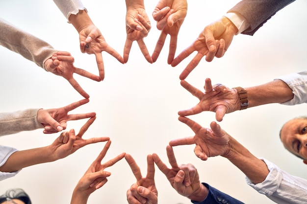 Group of business workers standing doing symbol with fingers together at the office