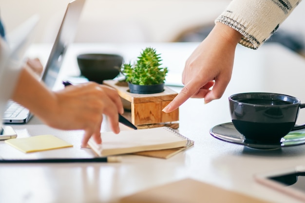 Group of businessman discussing, writing and pointing finger at notebook on the table in office