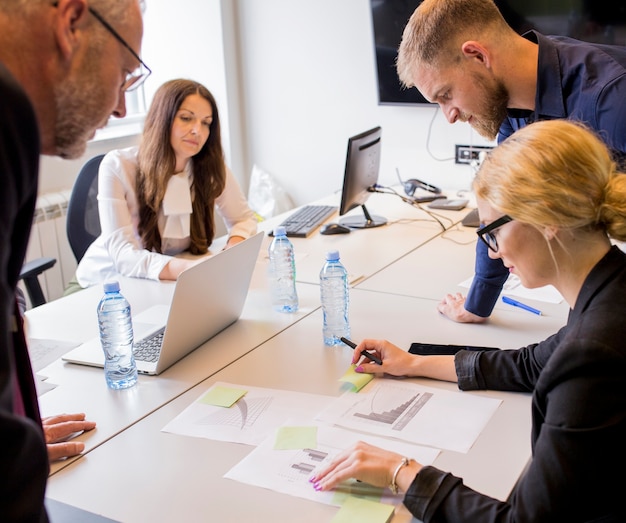 Foto gruppo di uomini d'affari analizzando il diverso tipo di grafico sul tavolo in ufficio