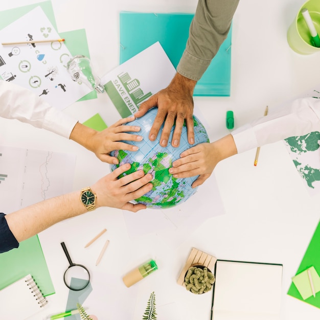 Group of businesspeople placing their hands on globe