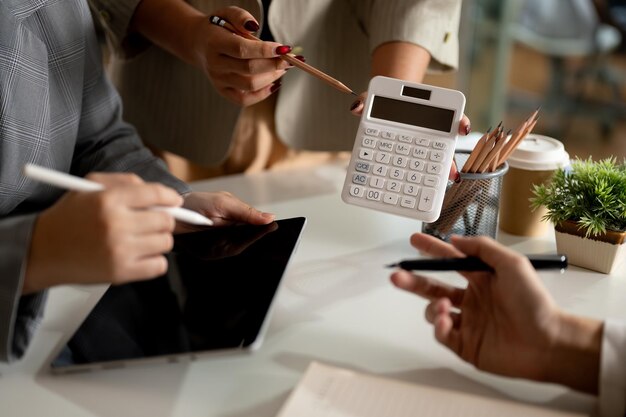 Group of businesspeople working together in the meeting showing the number on a calculator