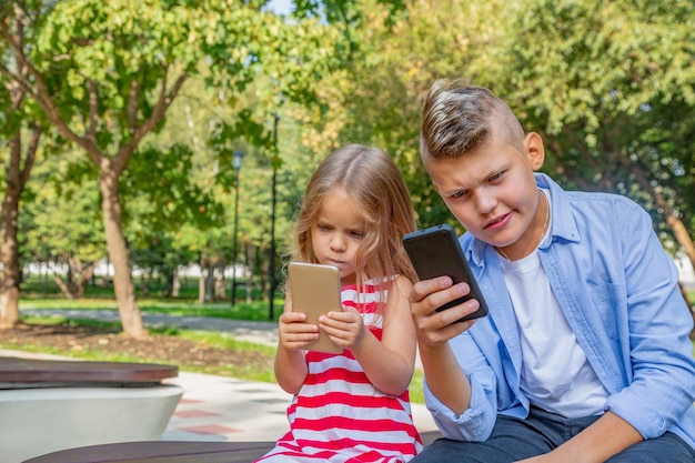 忙しい子供たちのグループは、自分の携帯電話のテキストメッセージのSMSを見て、外に座って遊んでいます