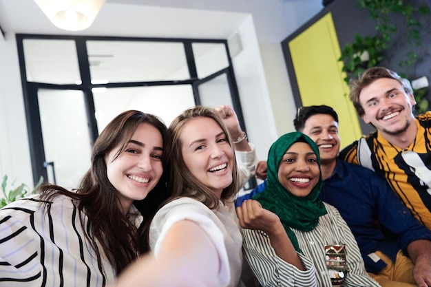 group of casual multiethnic business people during break from the work taking selfie picture while enjoying free time in relaxation area at modern open plan startup office