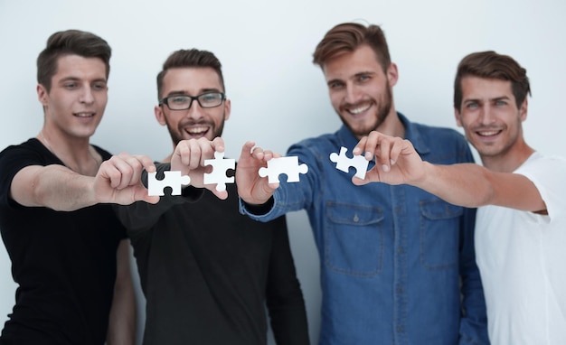 Group of casual people holding white puzzles in hands on a gray background