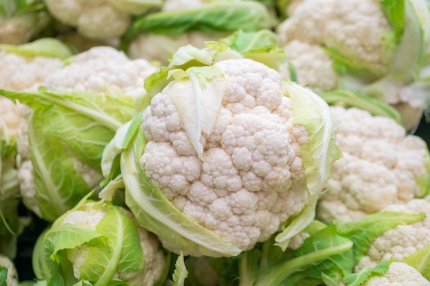 Group of cauliflowers with green leaves at market.