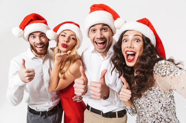 Group of cheerful friends dressed in red hats standing isolated over white