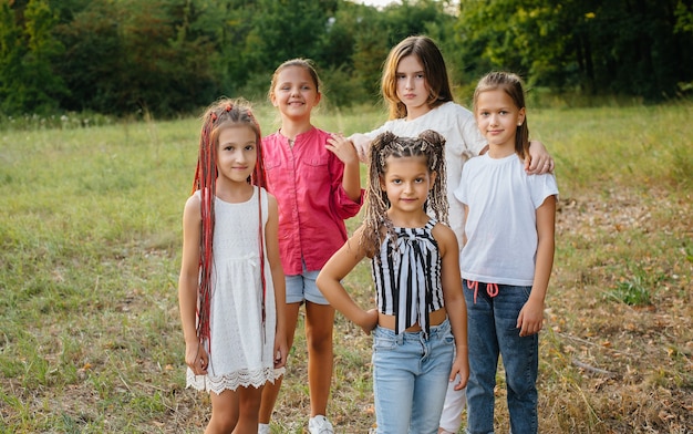 Foto un gruppo di ragazze allegre sorride e gioca nel parco durante il tramonto. campo estivo per bambini.