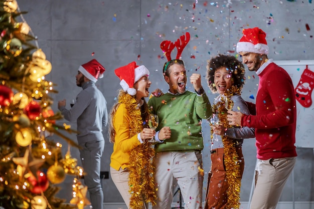 Photo group of cheerful multicultural colleagues celebrating christmas eve in their firm.