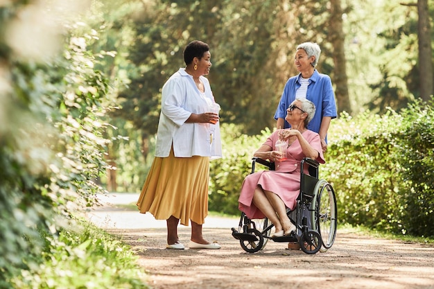 Группа веселых пожилых женщин, наслаждающихся совместной прогулкой в парке