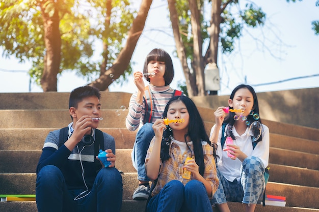 Group of child blowing soap bubbles and having fun in summer park outdoors