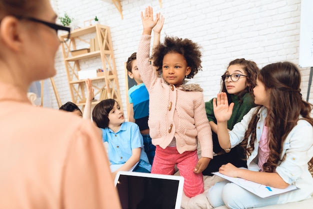 Group of children are pulling hands to answer teacher.