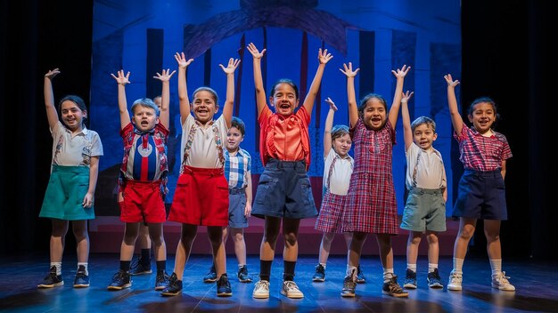 a group of children are on stage with their arms raised