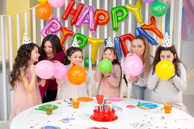 子供たちのグループが子供の誕生日を祝い、楽しく過ごす 子供と親が風船を膨らませる