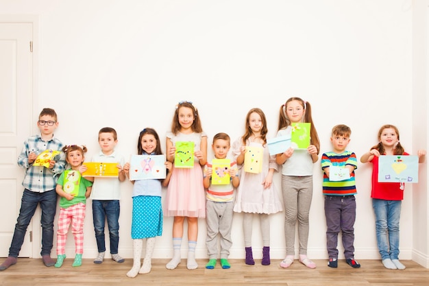 Group of children holding their handmade crafts after master class over a white background
