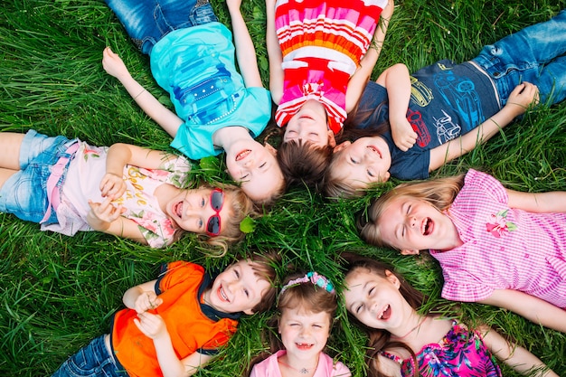 A group of children lying on the green grass in the Park.