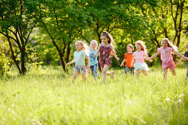 A group of children playing and running in the park on a green gozon.