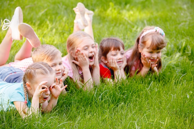 A group of children playing and running in the park on a green gozon.