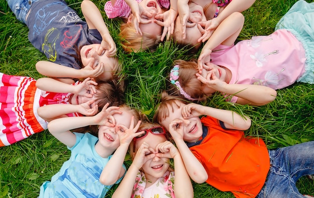 A group of children playing and running in the park on a green gozon.