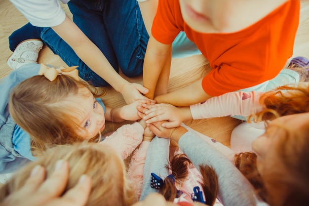 Group of children putting their hands together indoors, friedly concept