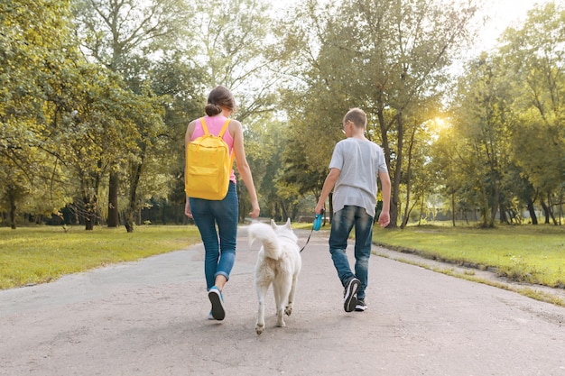 白いハスキー犬と一緒に歩いている子供たちのグループ