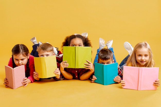 Foto gruppo di bambini che coprono i loro volti di libri