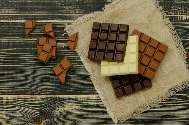 さまざまな色のチョコレートバーのグループさまざまな種類のお菓子の盛り合わせ素朴な木製の背景にチョコレートの盛り合わせ