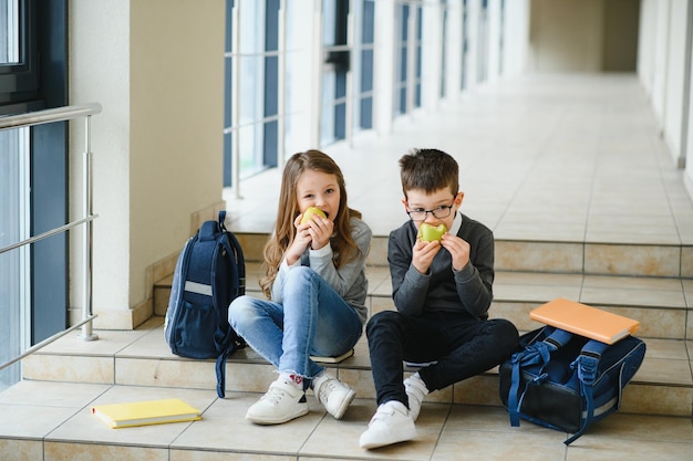 リンゴと笑顔の女の子に焦点を当てて休憩中に昼食をとっているクラスメートのグループ