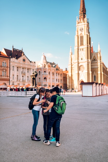 Group of classmates looking at smart phone on school excursion