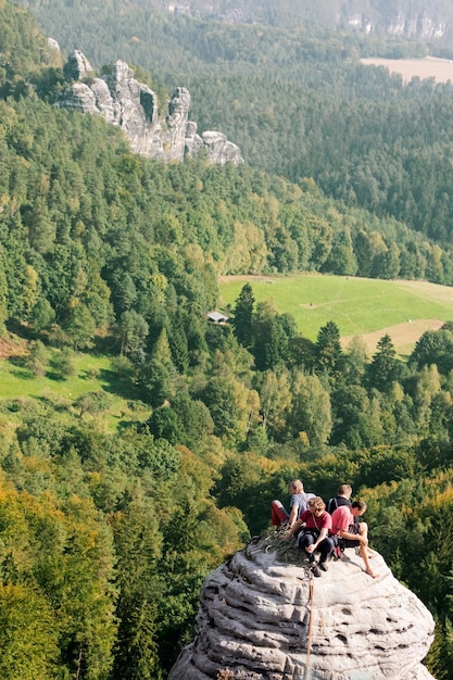 Group of climbers on the top of the round rocks on the forest\
background