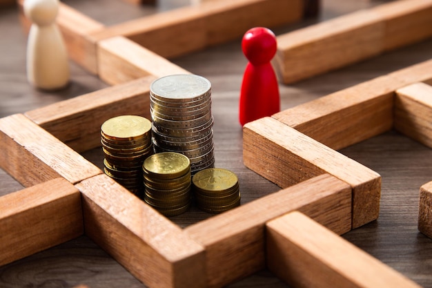 Foto gruppo di mucchi di monete nel gioco del labirinto costruito da blocchi di legno trova un modo per il concetto di risorsa denaro