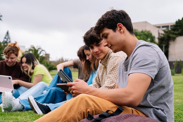 Group of college students using tablets on campus grass