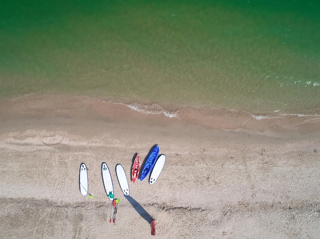 Group of color boards for stand up paddle surfing or SUP lying on beach at sea waves background at summer day