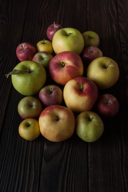 Group of colored apples of different sizes on a wooden surface