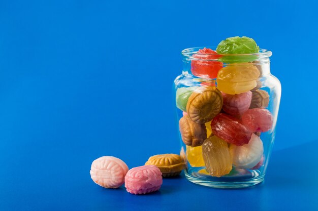 Gruppo di caramelle colorate in barattolo di vetro su sfondo blu. concetto di negozio di dolciumi e dolci. foto d'archivio.