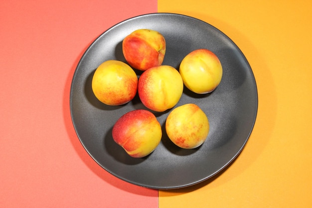Group of colorful nectarine fruits or peach on a black plate Coloredl background Healthy food