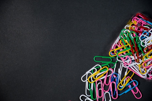 Group of colorful paper clips together with their boxes on a\
black background black space for text