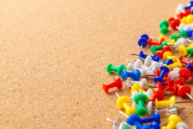 Group of colorful push pins on cork bulletin board