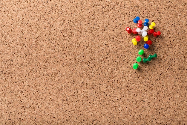 Group of colorful push pins on cork bulletin board