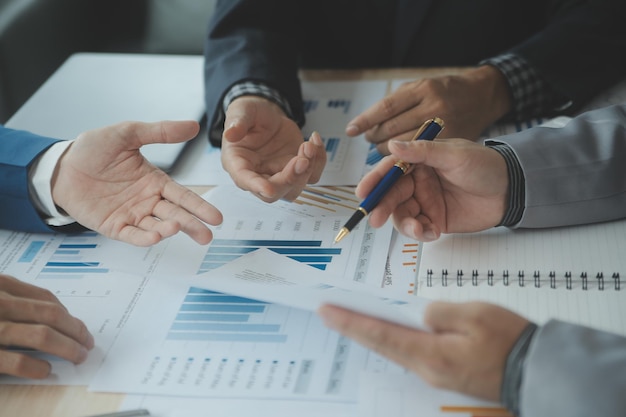 Group of confident business people point to graphs and charts to analyze market data balance sheet account net profit to plan new sales strategies to increase production capacity