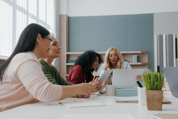 Group of confident mature women discussing business while having meeting in the office