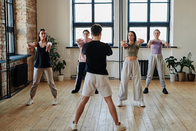 Photo group of contemporary teenagers looking at dance instructor in studio