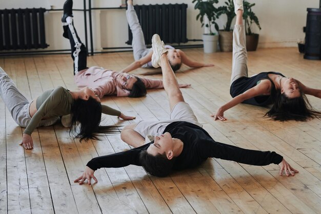 Group of contemporary teenagers in stylish activewear exercising on the floor